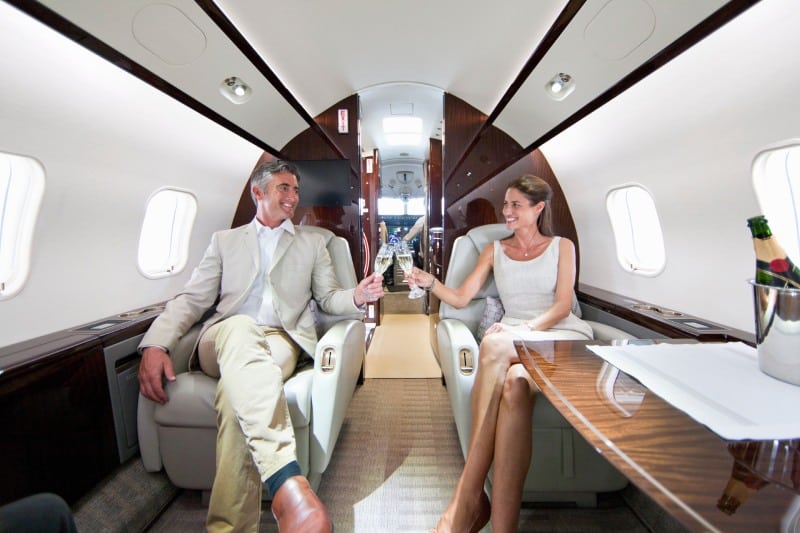 A couple on board a private jet drinking champagne