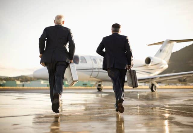 Two people in suits walk towards an on-demand jet charter