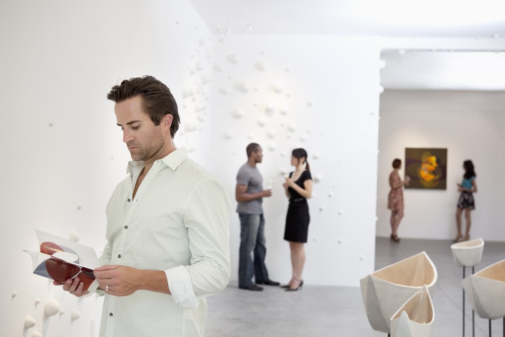 A group of people take in the art at a bright and inviting exhibit.