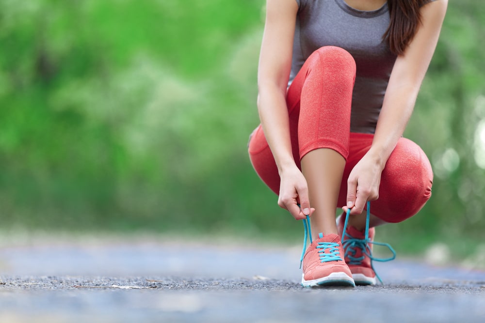 A woman laces up her running shoes.