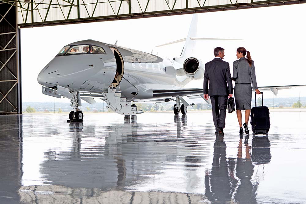 Two business people walking towards a private jet in a hangar