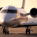 A green private jet sits on a runway